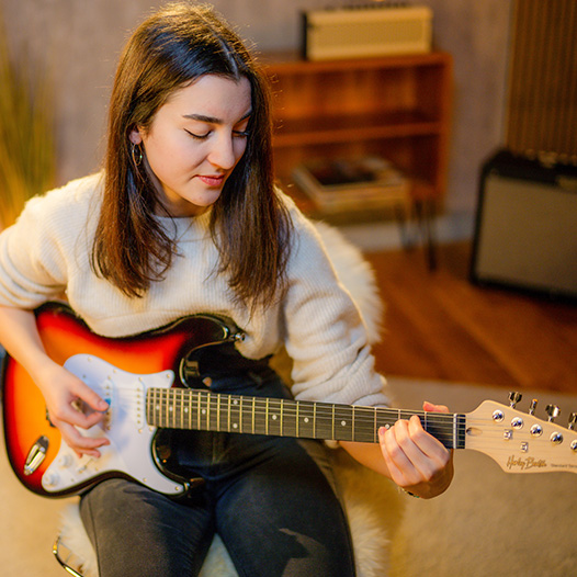 Young woman learning Harley Benton electric guitar